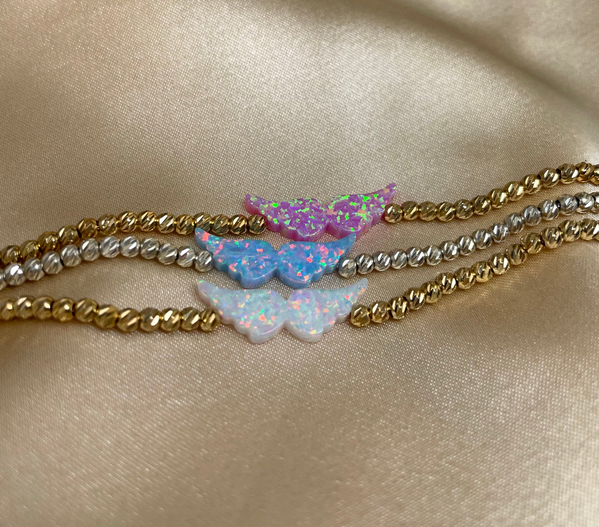 Three butterfly-shaped bracelets on a satin surface