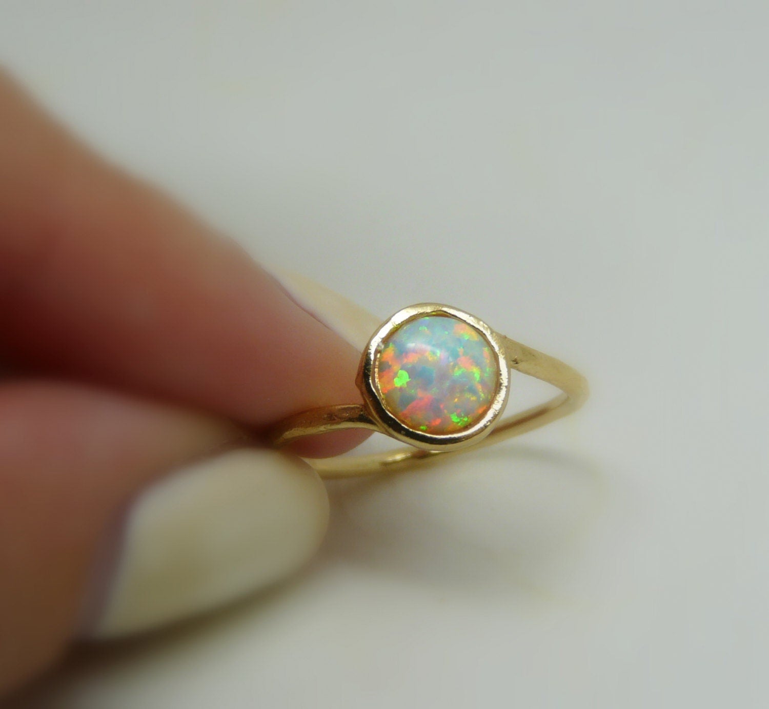 A gold-filled opal ring with a white opal stone, viewed from the side, showing the band and the setting.