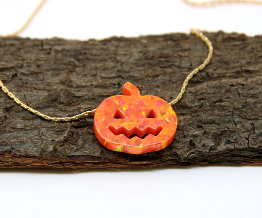 An opal pumpkin charm necklace displayed on a wooden surface.