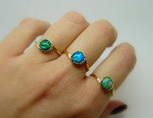 A set of three gold-filled rings with opal stones, displayed on a hand, showcasing the rings from different angles.
