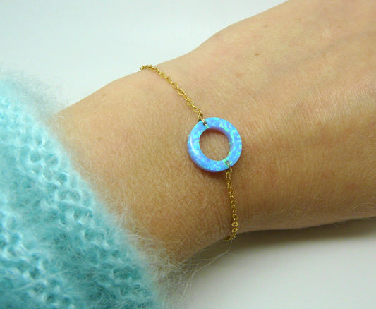 An opal circle charm bracelet on a gold-filled chain, displayed on a person's wrist.
