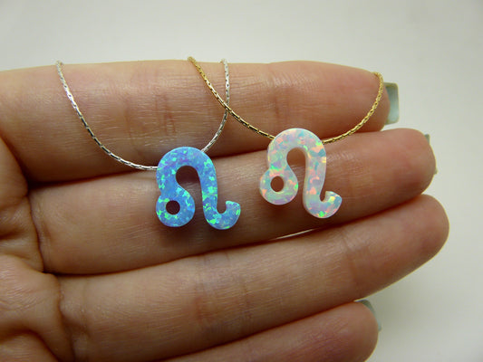 Two opal Leo zodiac pendant necklaces resting on a hand, one with a gold chain and the other with a silver chain.