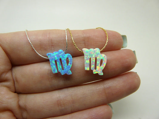 Two opal Virgo zodiac charm necklaces held in a hand, one with a silver chain and the other with a gold-filled chain.