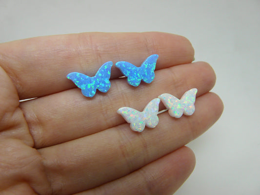 A hand holding three pairs of butterfly-shaped stud earrings, with the pairs displaying blue, white, and pink opal colors.