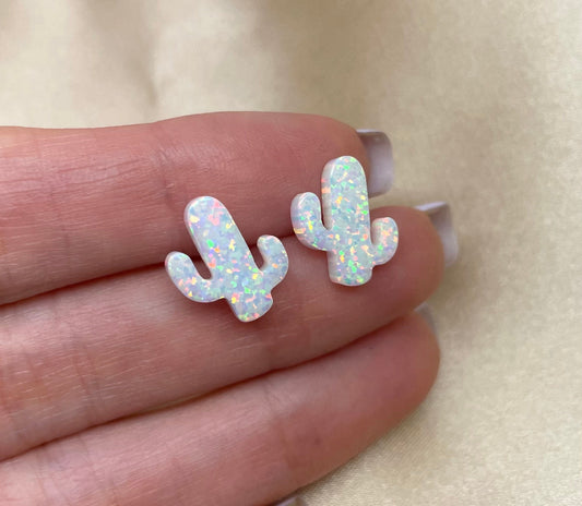 A pair of sterling silver cactus-shaped earrings with opal inlays, displayed on a hand.