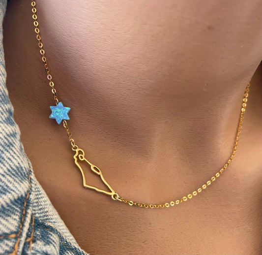 A gold-filled necklace with a Israel map pendant and an opal star of David accent, worn by a person with a denim shirt in the background.