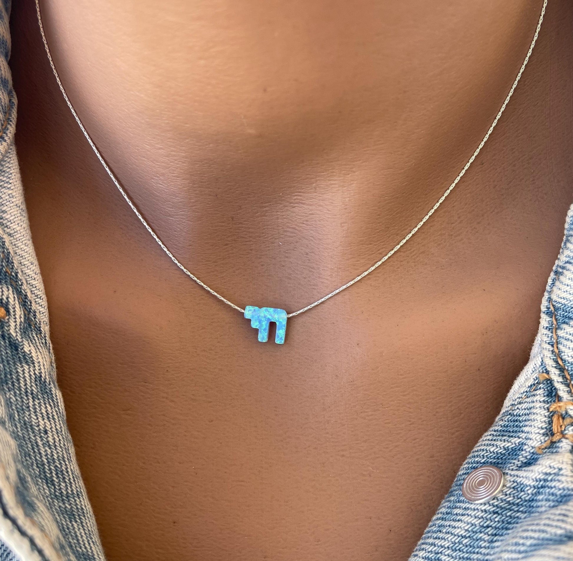 A woman wearing a blue opal Chai necklace, with the pendant displayed on her collarbone.