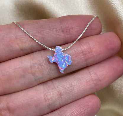 Necklace with a colorful pendant held in a hand against a beige background