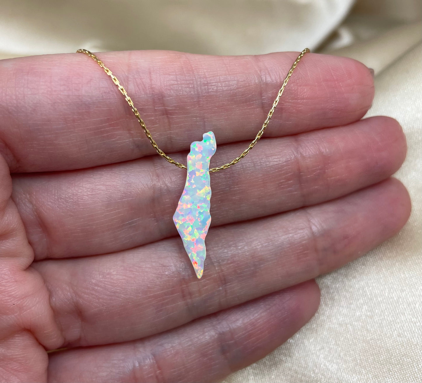 Opal stone necklace on a hand with a neutral background
