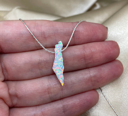 Necklace with a colorful pendant held between fingers on a neutral background