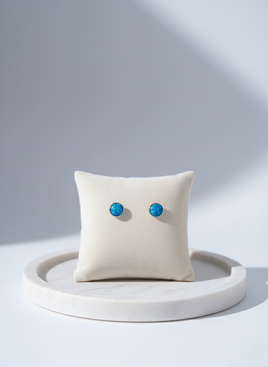 Pair of turquoise earrings on a white cushion with a light gray background