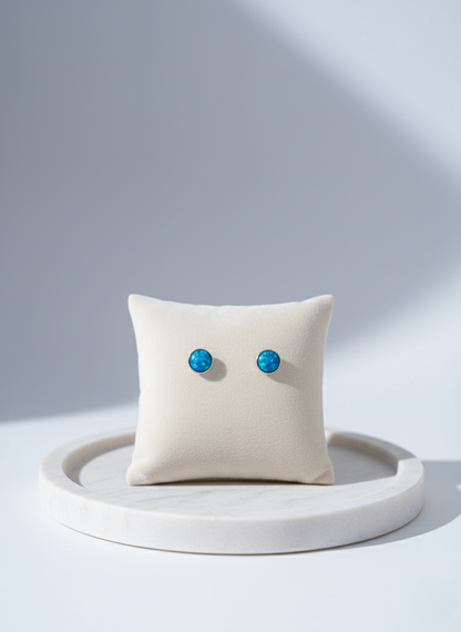 Pair of turquoise earrings on a white cushion with a light gray background
